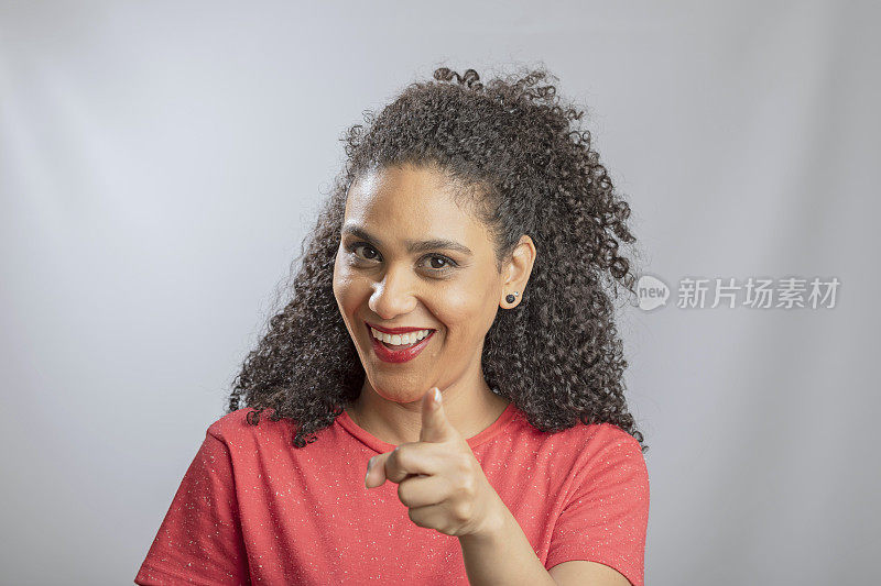 Brazilian young woman with curly hair pointing aiming